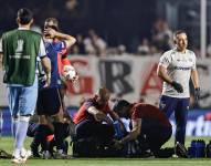 Juan Izquierdo (abajo) de Nacional es atendido por personal de la salud este jueves, en el partido de vuelta de octavos de final de la Copa Libertadores