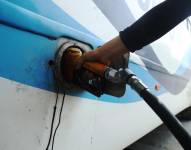 Imagen de una persona cargando gasolina a un bus de transporte público.
