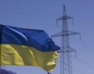 Imagen de archivo de banderas ucranianas junto a una torre de alta tensión del sistema eléctrico, en Dnipro, Ucrania.