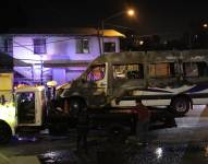 Trabajadores retiran un bus de transporte público incinerado en Tijuana, Baja California.
