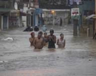 Personas caminan por calles inundadas debido al paso de la tormenta tropical Franklin en Santo Domingo República Dominicana