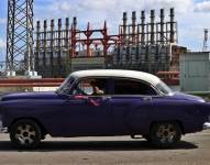 Un auto clásico pasa frente a una de las plantas de generación eléctrica en el puerto de La Habana (Cuba), en una fotografía de archivo.