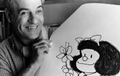Quino sosteniendo un dibujo de Mafalda.