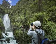 Un turista tomando fotos de la Cascada de Peguche.