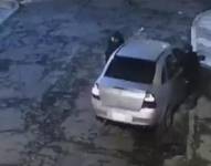 Momento en el que dos individuos se acercan a un carro para asaltar a sus ocupantes.