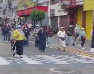 Personas cubiertas el rostro recorren las calles de Otavalo.