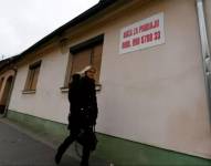 Una transeúnte pasa frente a una casa vacía con un anuncio de venta en el este de Croacia, en diciembre de 2021.