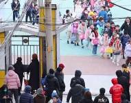 Niños salen de una escuela usando mascarillas