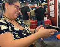 Una veterana de guerra examina un arma durante la convención de la NRA.