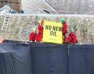 Una foto puesta a disposición por Greenpeace, Reino Unido, muestra a activistas sosteniendo una pancarta para protestar por la perforación petrolera en el techo del primer ministro británico.