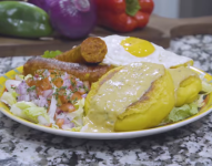 Imagen de un plato de llapingacho servido con salsa de maní, chorizo, salsa de cebolla, y un huevo frito.
