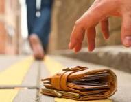 Billetera en el piso y una persona trata de levantarla.