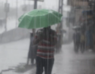 Imagen de una persona sosteniendo un paraguas durante una lluvia fuerte.