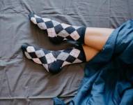 Mujer usando medias en una cama.