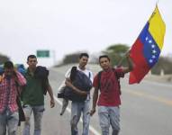 Imagen de migrantes sosteniendo la bandera de Venezuela.