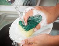 Woman hand washing dishes over the sink in the kitchen