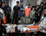 Un hombre herido es llevado en camilla para recibir asistencia después de que un ataque impactara en el hospital Bautista Al-Ahli.