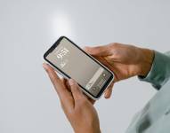 Hombre sosteniendo su celular con notificación de mensaje en WhatsApp.