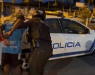 Un agente de la Policía Nacional lleva al sospechoso al patrullero, en Esmeraldas.