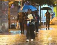 Imagen de una mujer caminando con un paraguas en una noche lluviosa en Quito.