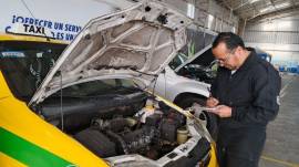 Uno de los técnicos de matriculación revisando el motor de un vehículo.