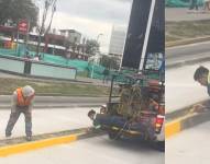 El trabajador se apoya en una camioneta para pintar el bordillo de forma más fácil.