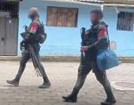 Los dos individuos fuertemente armados mientras caminan en el sector de Las Juntas.