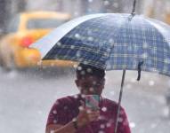 Un ciudadano se protege de la lluvia con un paraguas.
