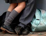 Pies de dos niños y mochilas en el piso