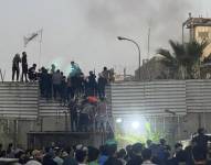 Manifestantes de Irak trepando un muro de la embajade de Suecia en Bagdad.