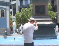 Foto de una persona quitándose la gorra para mojar su cabeza con agua de la fuente enfrente de la Iglesia La Merced, en el centro de Guayaquil, en marzo de 2024.