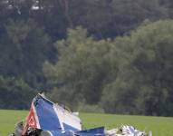 Dos personas observan los restos de una avioneta accidentada.