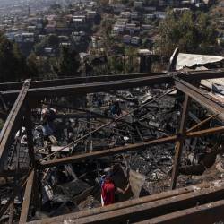 Personas retiran escombros de las viviendas destruidas por un incendio en Valparaíso, en Chile.
