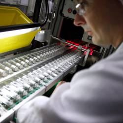 Imagen de un empleado trabajando en una línea de producción de vacunas contra la influenza.