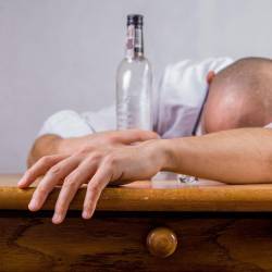 Persona acostada sobre una mesa después de haber ingerido alcohol. Foto: Pixabay / Referencial
