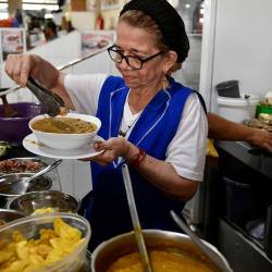 Una comerciante sirviendo un plato de fanesca en un mercado municipal de Guayaquil.
