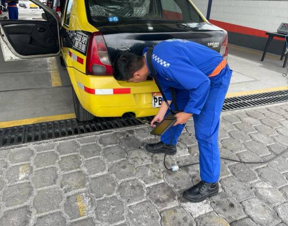 Los técnicos del centro de revisión Verify Car Mejía revisan los gases de un taxi.