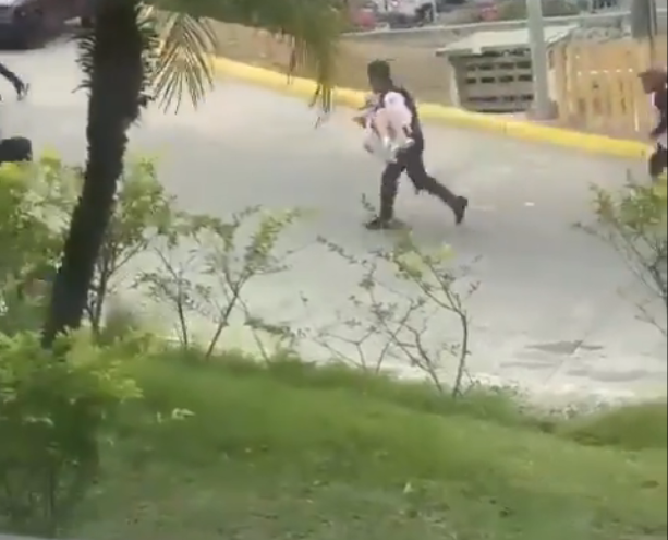 Imagen en el que una persona traslada a una estudiante herida al hospital Los Ceibos.