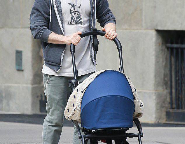 Daniel junto a su hijo recién nacido, quien se encuentra dentro del carrito de niños.