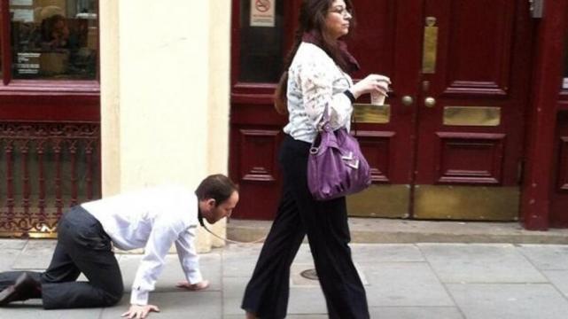 Una mujer pasea a un hombre como mascota