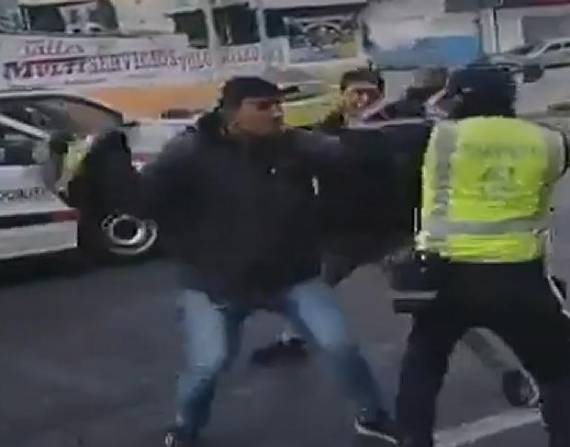 Momento en el que un motociclista golpea con un casco a un agente civil de tránsito.