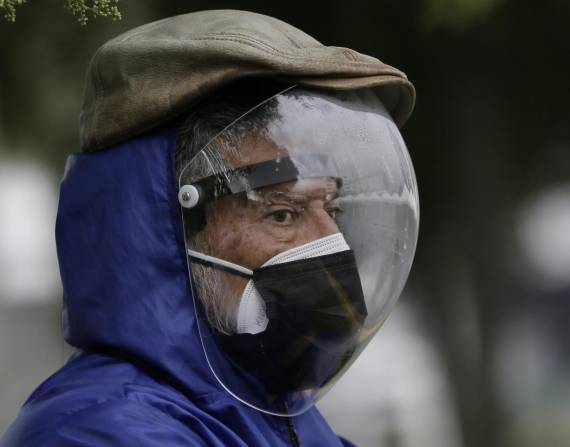 Un hombre vestido con un protector facial completo y una máscara doble para evitar el contagio del COVID-19 espera su turno para ser vacunado, afuera de un centro de vacunación del Instituto del Seguro Social en Quito, Ecuador, el jueves 6 de mayo de 2021. (AP Foto/Dolores Ochoa)