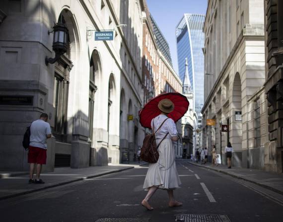 Una mujer en Reino Unido se protege del calor con una sombrilla.