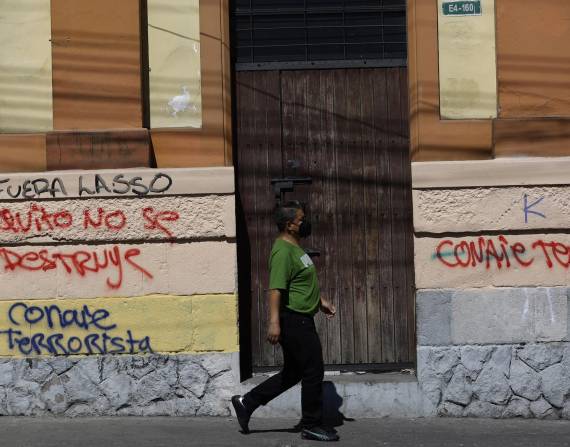 Una mujer camina frente grafitis este viernes en Quito, donde se concentró la mayor parte de las manifestaciones.