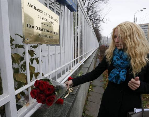 Una mujer coloca flores en las afueras de la Embajada de Francia en Rusia.