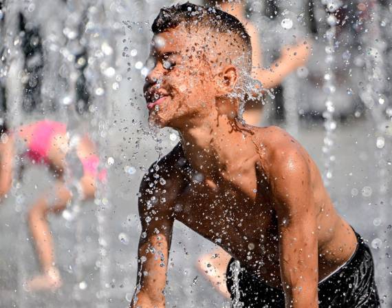 Un niño se refresca en una fuente del centro de Duisburg (Alemania) por las altas temperaturas.