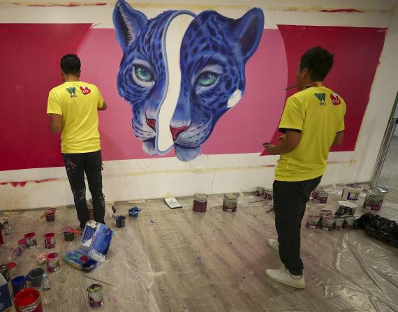 Artistas dibujan un jaguar en un centro comercial de Quito.