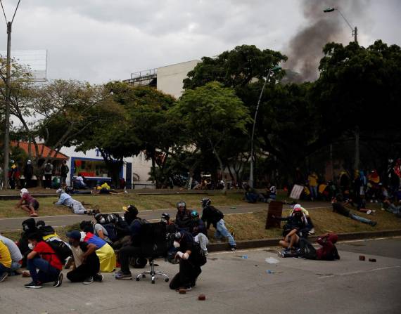 Manifestantes se cubren durante un enfrentamiento con la policía, en una jornada de protestas el 28 de mayo de 2021 en Cali (Colombia).