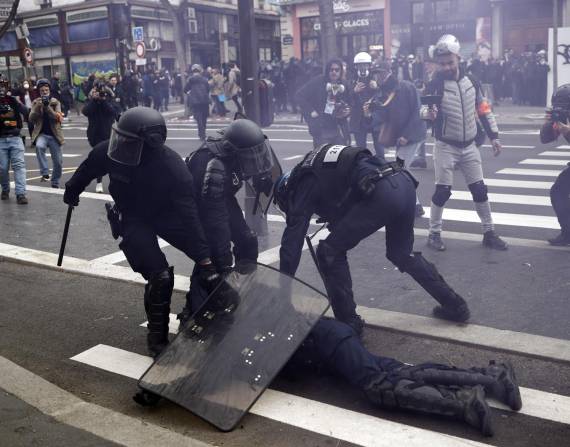 Policías franceses protegen a un colega herido durante enfrentamientos con manifestantes en una protesta contra la reforma del sistema de pensiones en París este jueves.