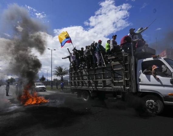 Manifestantes antigubernamentales pasan frente a una barricada en llamas durante protestas contra el gobierno del presidente Guillermo Lasso.